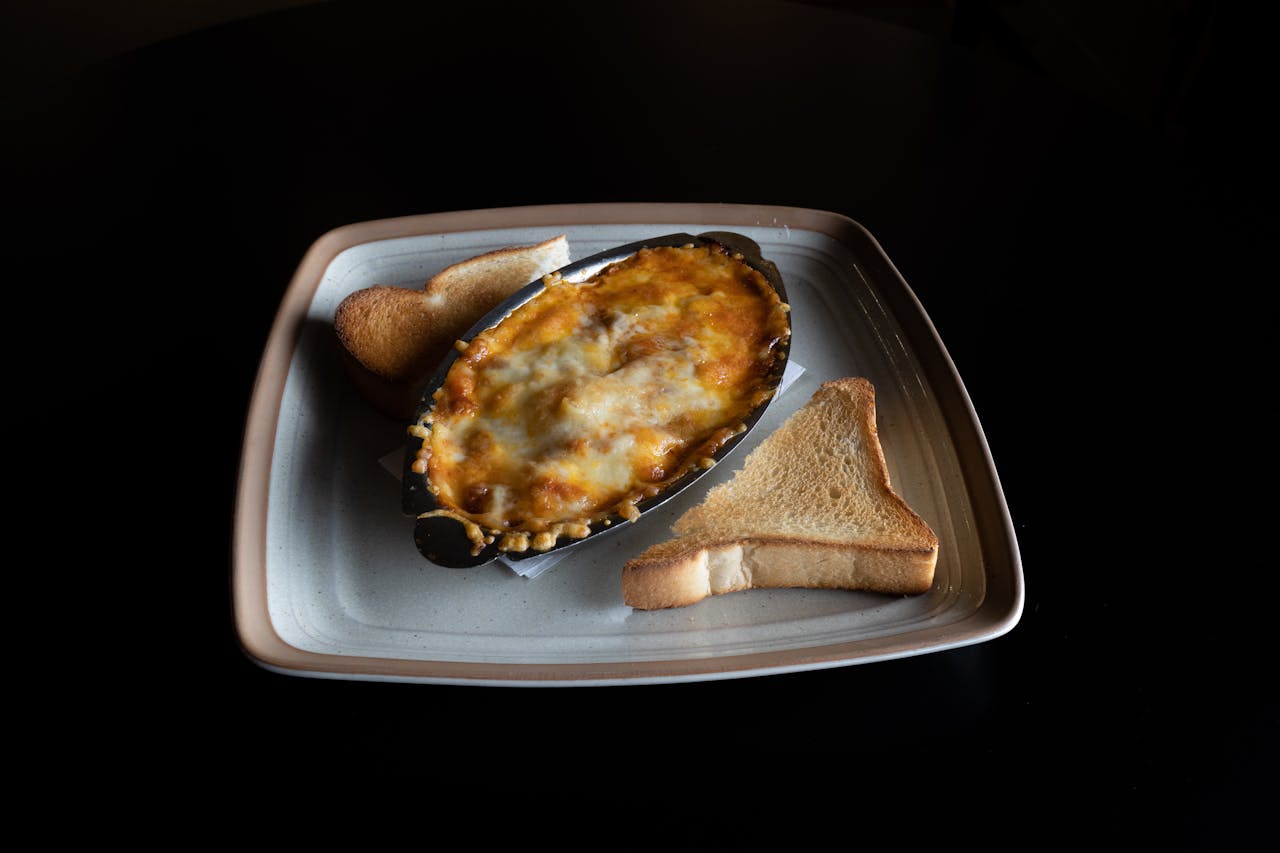Delicious baked lasagna served with slices of toasted bread on a plate, perfect for a savory meal.