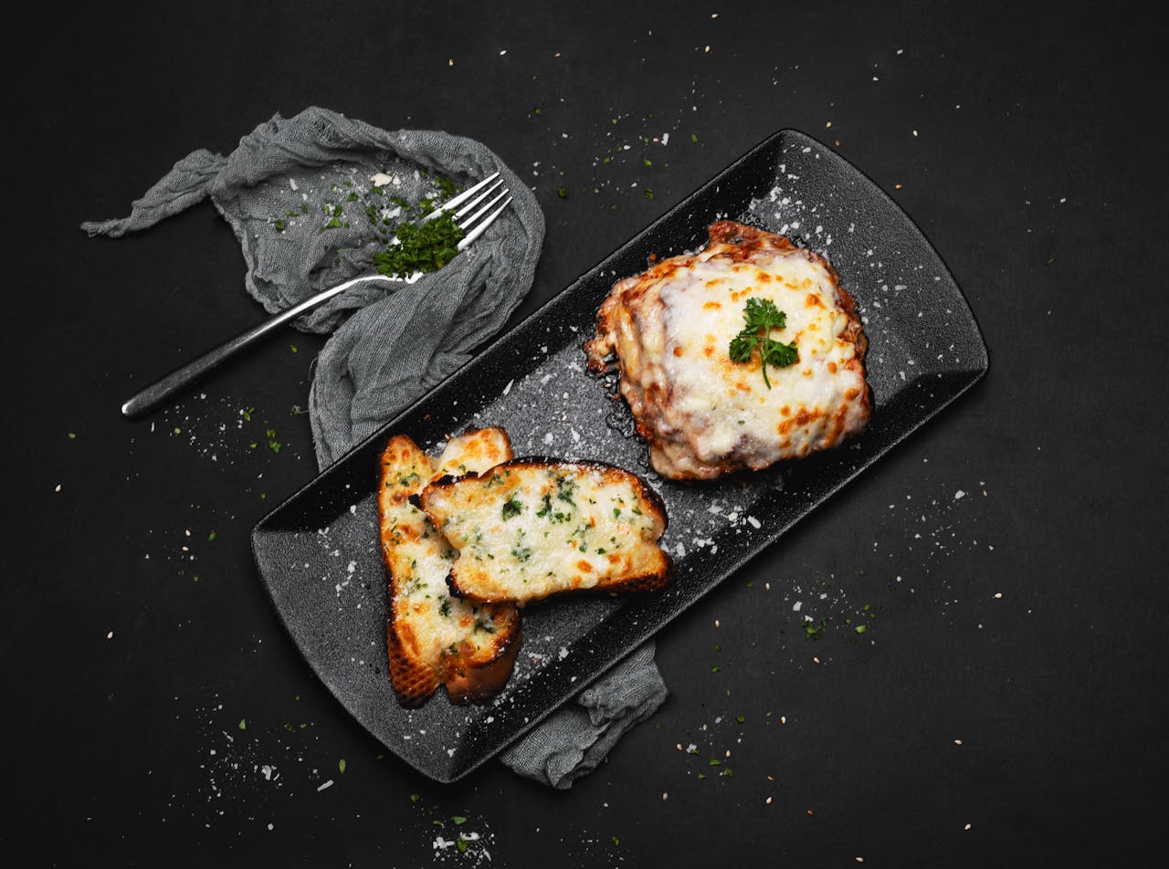 Indulge in a mouthwatering serving of baked lasagna topped with melted cheese and served with garlic bread.